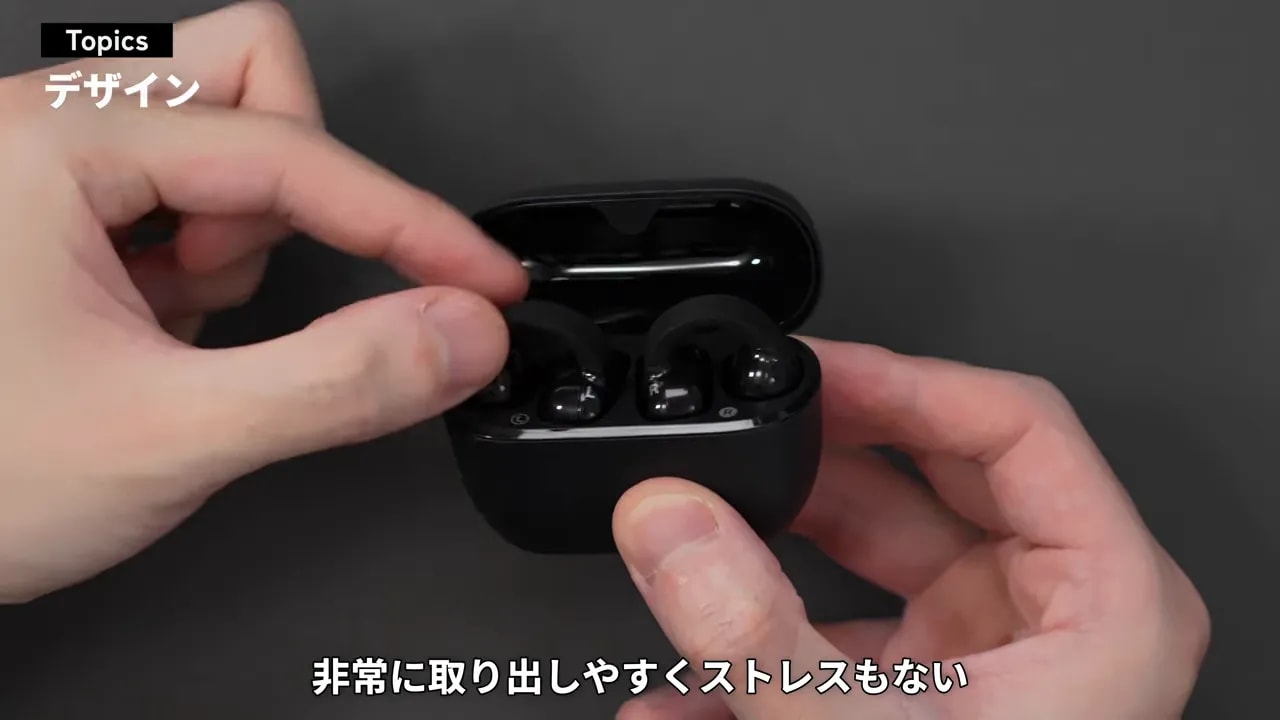 開いた充電ケースからイヤーカフ型イヤホンを取り出す手