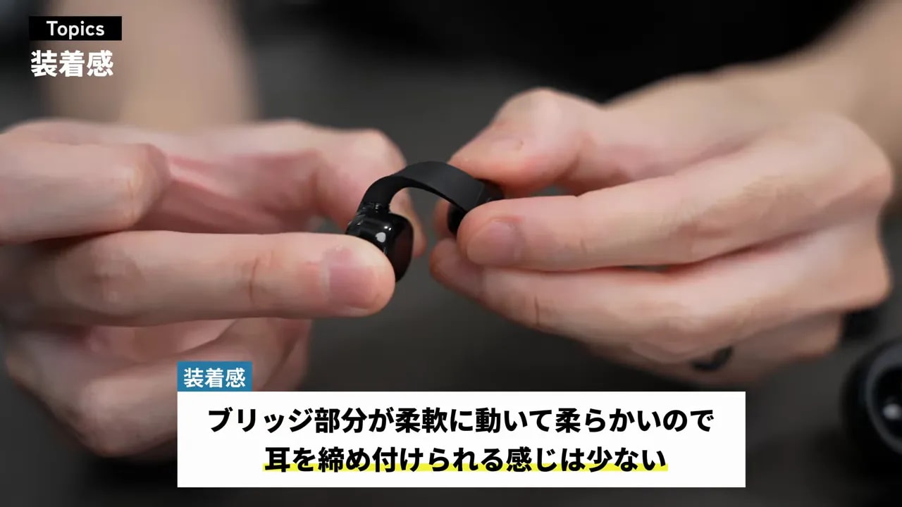 ブリッジ部分を指で曲げて柔軟性を見せているイヤホン